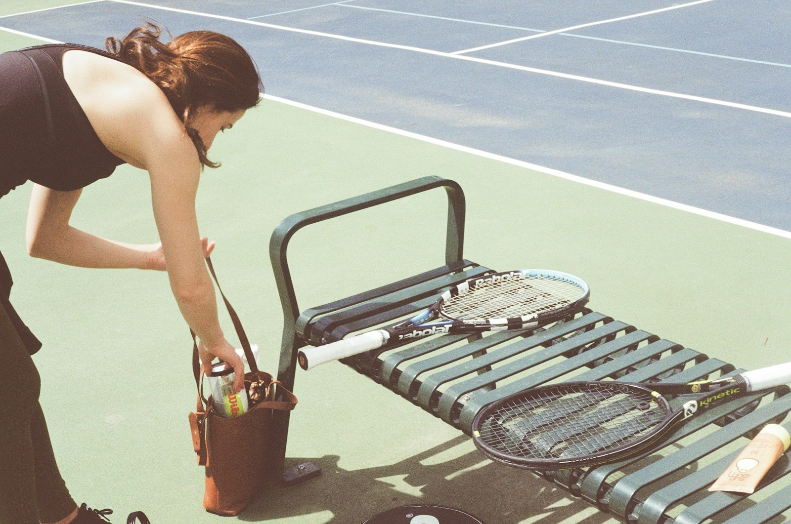 A woman bending over to pick up a tennis racket